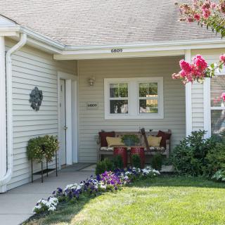 A cozy front porch with a bench and vibrant flowers in a well-maintained garden.