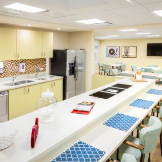 A modern kitchen interior with a long countertop, seating, and contemporary appliances.