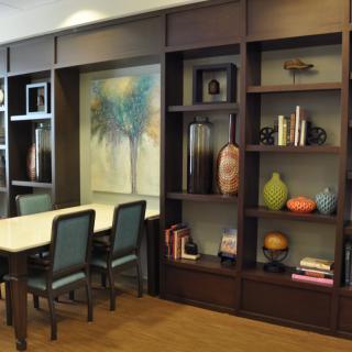 A modern interior dining area featuring a large bookshelf and artistic decor.