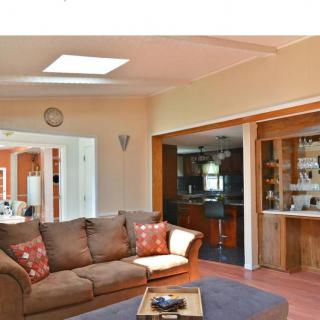 A cozy living room with an open-plan design, featuring a comfortable sofa, a skylight for natural lighting, and a view into the kitchen area.