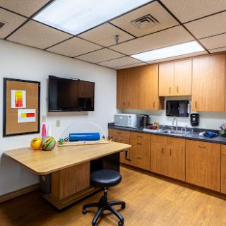 A cozy breakroom featuring a kitchenette with modern appliances, a desk, and inviting decor.