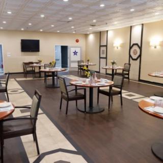 A spacious and well-lit restaurant dining area with neatly arranged tables and chairs.