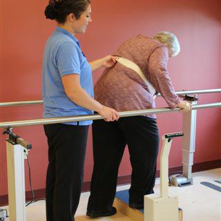 A physical therapist assists an elderly patient during a rehabilitation session.