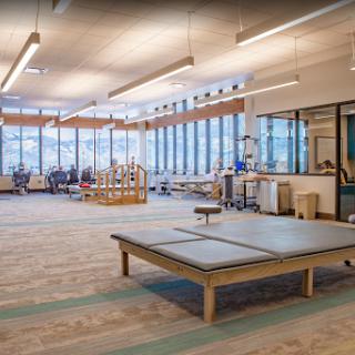 A spacious and well-lit therapy room designed for rehabilitation with modern equipment and large windows providing natural light.