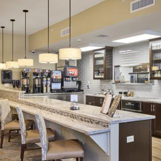 A modern kitchen interior featuring a cafe-style counter with seating and pendant lights.