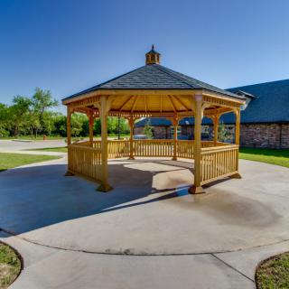 A wooden gazebo under a clear blue sky in a park setting.