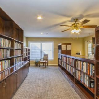 A cozy reading area with bookshelves lining the walls and a chair by the window.