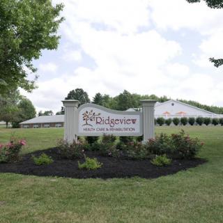 A welcoming sign in a landscaped area, indicating a facility or event space.