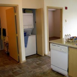 An apartment interior featuring a compact kitchen and laundry area.