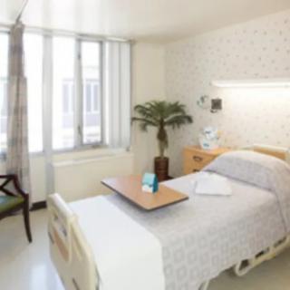 A clean and well-lit hospital room with a single bed and medical equipment.