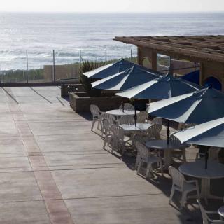 A scenic patio with umbrellas and seating overlooking the ocean.