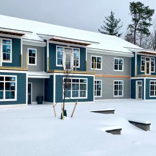 A snow-covered modern building surrounded by trees in a winter setting.