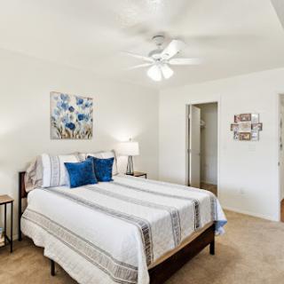A cozy and inviting bedroom featuring a queen-sized bed, stylish decor, and a ceiling fan.
