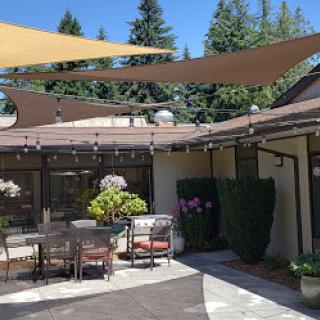 A well-designed outdoor patio featuring shade sails, seating arrangements, and beautiful greenery.