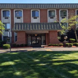 A brick building with a neatly landscaped entrance and trees.