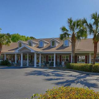 A residential building with a covered entrance and palm trees in a sunny setting.