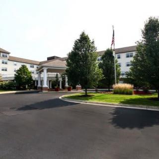 A well-maintained building with a circular driveway and landscaped gardens.