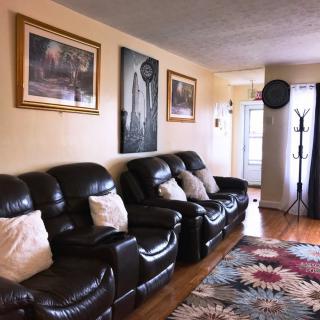 A cozy living room featuring leather sofas, wall art, and a colorful rug.
