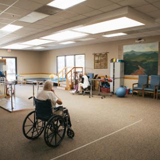 A spacious rehabilitation room equipped with therapy tools, accommodating individuals using wheelchairs.