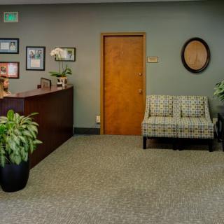 A welcoming office reception area with a desk, seating, and decorative plants.
