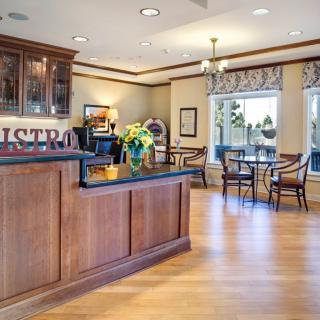 A cozy caf interior with a wooden counter and seating area, featuring ample natural light.