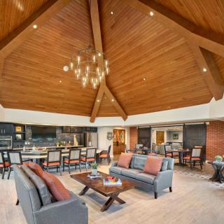 A spacious and modern living room with a wooden ceiling and elegant chandelier.
