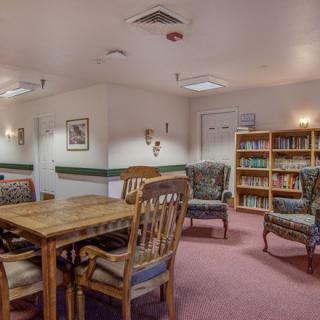 Cozy library reading room with bookshelves, tables, and chairs.