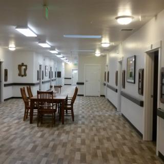 A well-lit hallway with tables and chairs arranged in the center, decorated with framed pictures on the walls.
