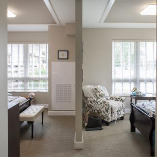 A bedroom interior showcasing a divided space with natural light streaming through large windows.