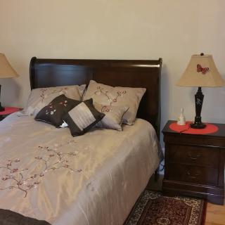 A cozy bedroom with a neatly made bed, flanked by nightstands and lamps.