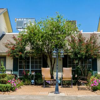 A quaint house with a well-maintained garden and outdoor seating.