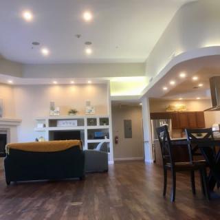 A spacious and modern open floor plan living area with a kitchen and dining space, featuring wood flooring and recessed lighting.