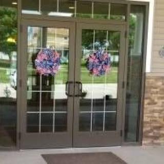 A glass entrance door adorned with colorful wreath decorations.