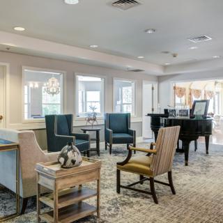 A spacious and elegantly furnished living room with a piano and various seating options.