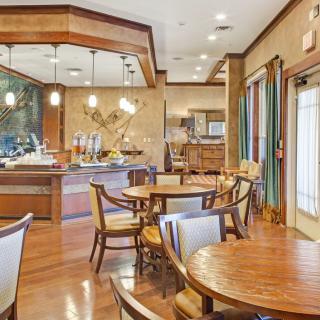 A spacious and well-appointed dining area with wooden tables and chairs, featuring elegant lighting and decor.