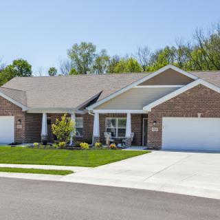 A beautiful suburban house with a well-maintained lawn and dual garages.