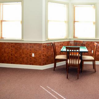 A small dining area with a table and chairs, illuminated by natural light from nearby windows.