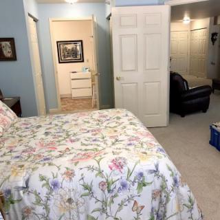 A cozy bedroom with a floral bedspread, blue walls, and an open closet.