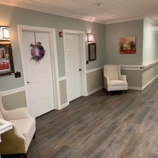 A cozy waiting area with comfortable chairs, soft lighting, and decorative elements like a wreath and artwork on the walls.