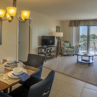 A modern living and dining area with stylish furnishings, a television, and access to a balcony.