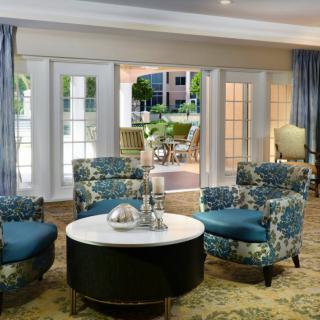 A stylishly decorated living room with floral armchairs and a round coffee table near large windows.
