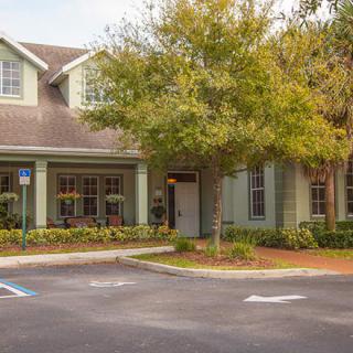 A residential building with a parking lot and landscaped surroundings.