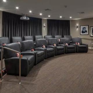A luxurious home theater with comfortable recliner seating and a projector.