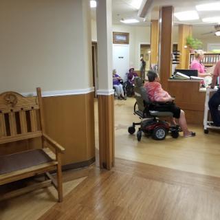 A view of a nursing home interior, showcasing the waiting area and residents using mobility aids.