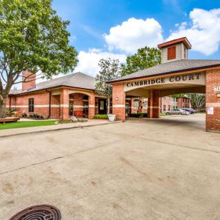 Entrance of a residential complex with a brick facade and driveway.