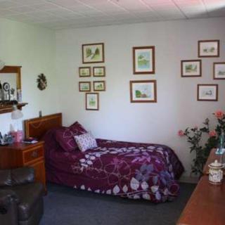 A cozy bedroom with a single bed, adorned with floral-themed decor and wall art.