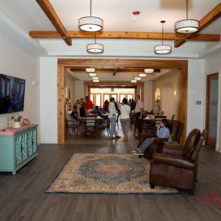 A cozy living room area with comfortable seating and people socializing in the background.