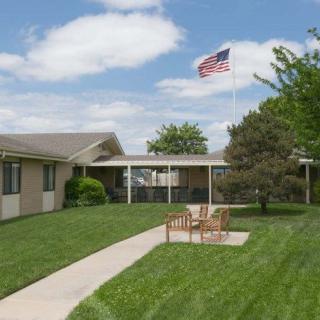 A building with a lush green lawn and outdoor seating, featuring an American flag in the background.