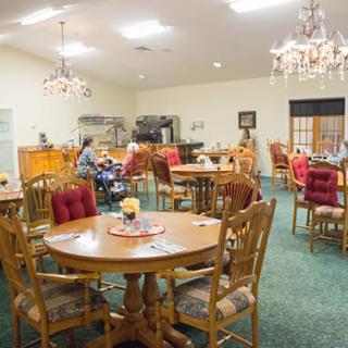 A cozy dining area with wooden tables and chairs, illuminated by elegant chandeliers.