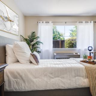 A bright and minimalist bedroom with a neatly made bed, large window, and stylish decor.